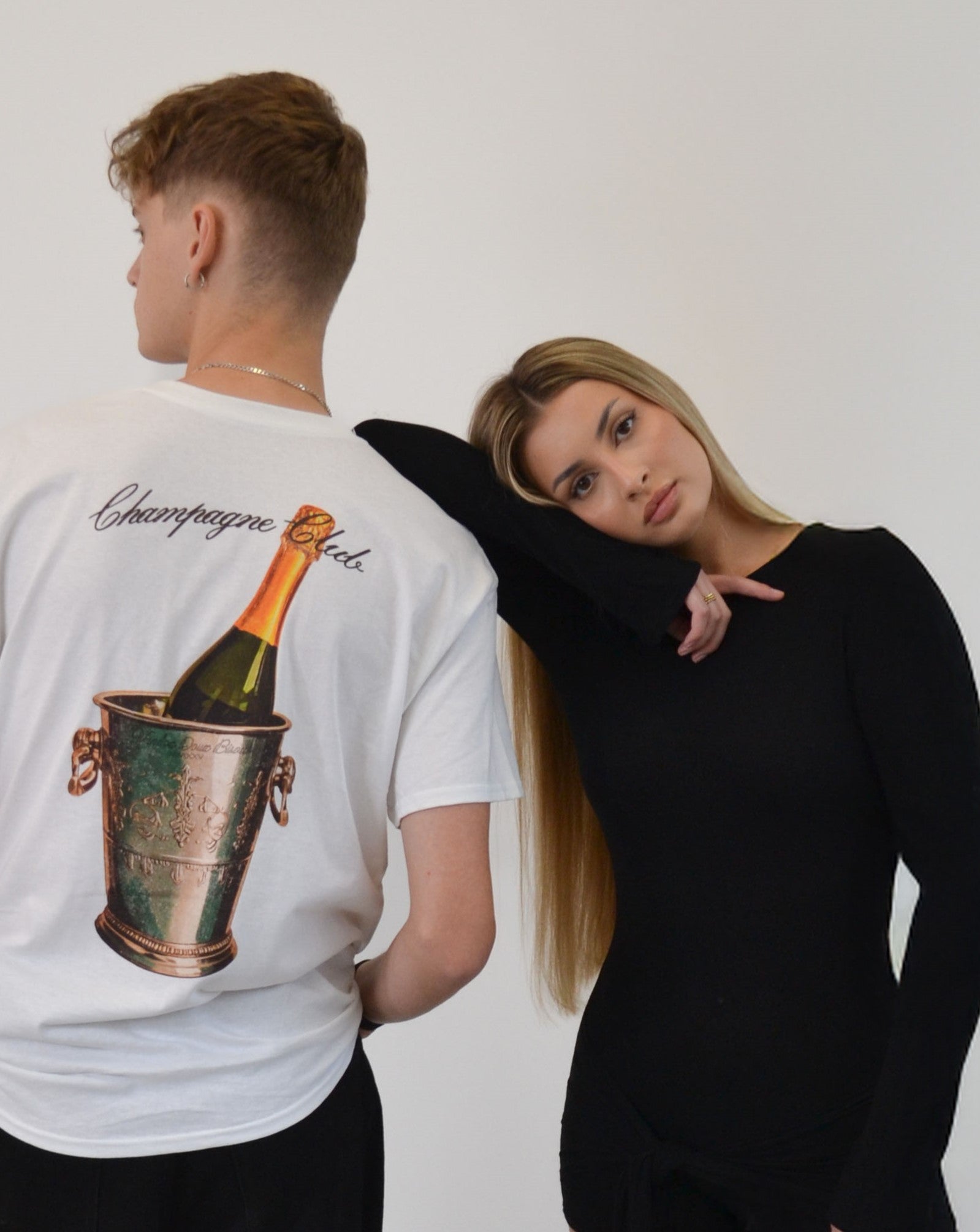 Male model wearing the Bubbly Society T-Shirt by Vandox - a premium white oversized tee featuring an elegant champagne bucket print and cursive “Champagne Club” script. A refined statement piece blending old-money sophistication with contemporary streetwear luxury.  Starboy old money shirt tshirt clothes vandox sacrevandox vandox clothes vandox clothing