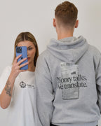 Male model wearing the Money Talks Hoodie in sport grey by Vandox - a premium oversized hoodie featuring a bold “Money Talks. We Translate.” print inspired by Wall Street culture. Designed for the confident and ambitious, this piece blends luxury streetwear with a statement-making financial aesthetic. Starboy old money hoodie sweatshirt clothes vandox sacrevandox vandox clothes vandox clothing