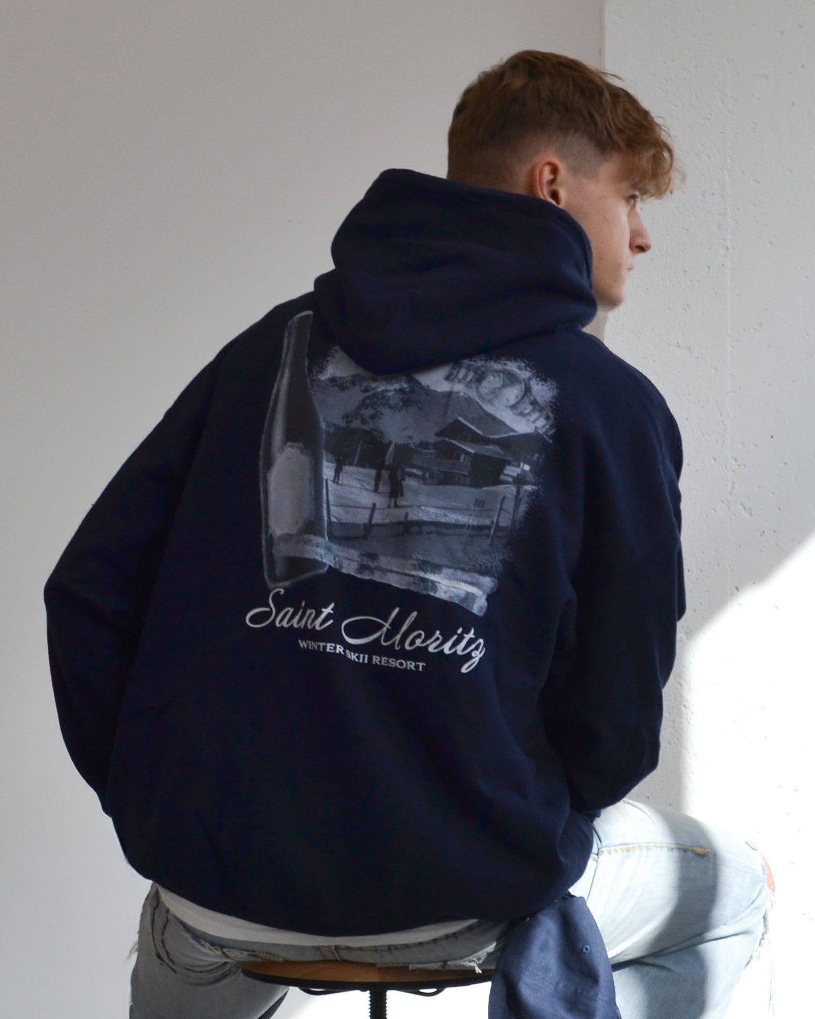 Male model wearing the Alpine Ski Club Hoodie in navy - a premium oversized hoodie featuring the “Saint Moritz Winter Ski Resort” graphic print. A timeless Vandox piece inspired by alpine luxury and après-ski culture, blending vintage mountain aesthetics with modern streetwear sophistication. Starboy old money hoodie sweatshirt clothes vandox sacrevandox vandox clothes vandox clothing