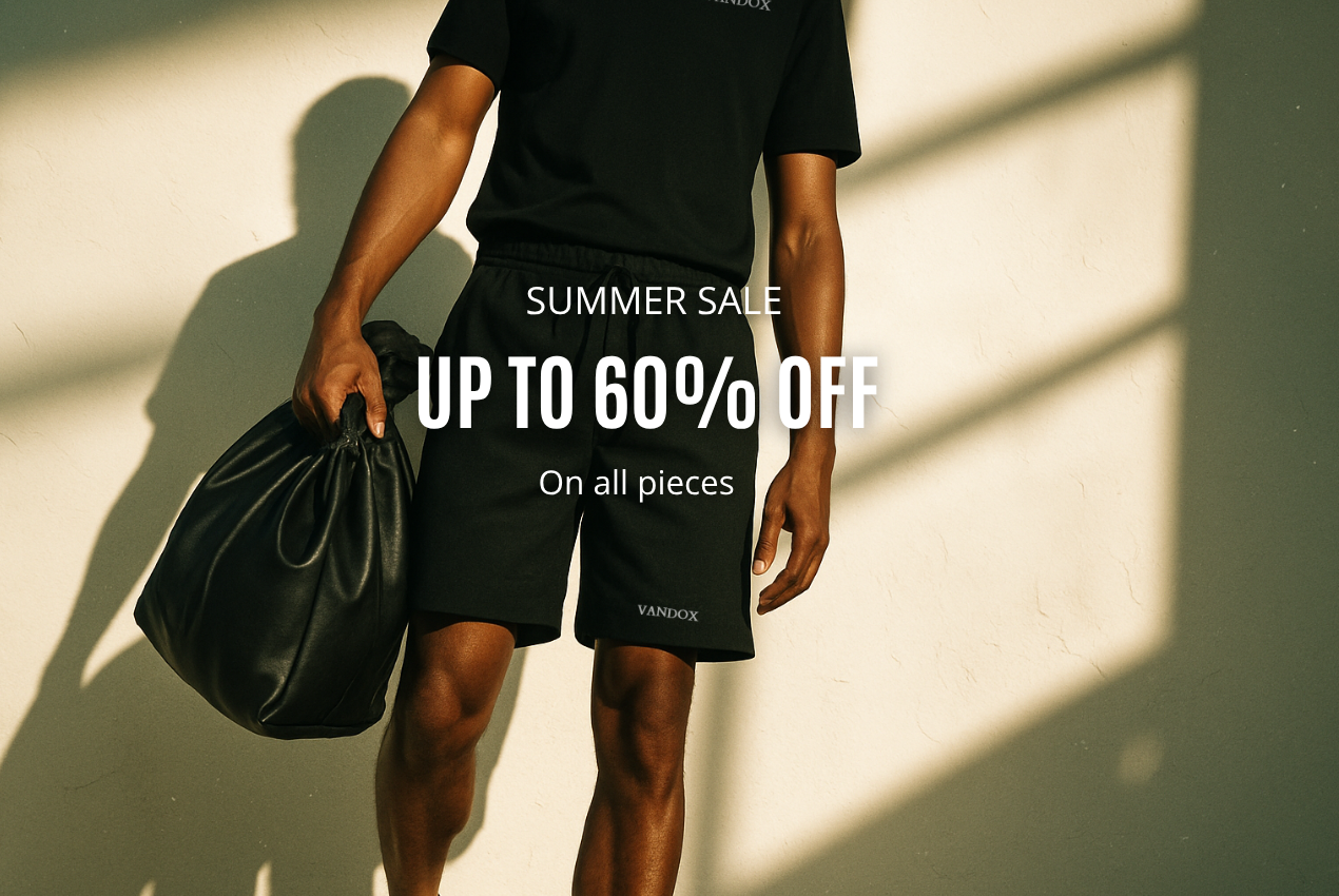 Male model standing in warm natural light wearing Vandox shorts and holding a leather bag, with summer sale promotional text displayed over the image.