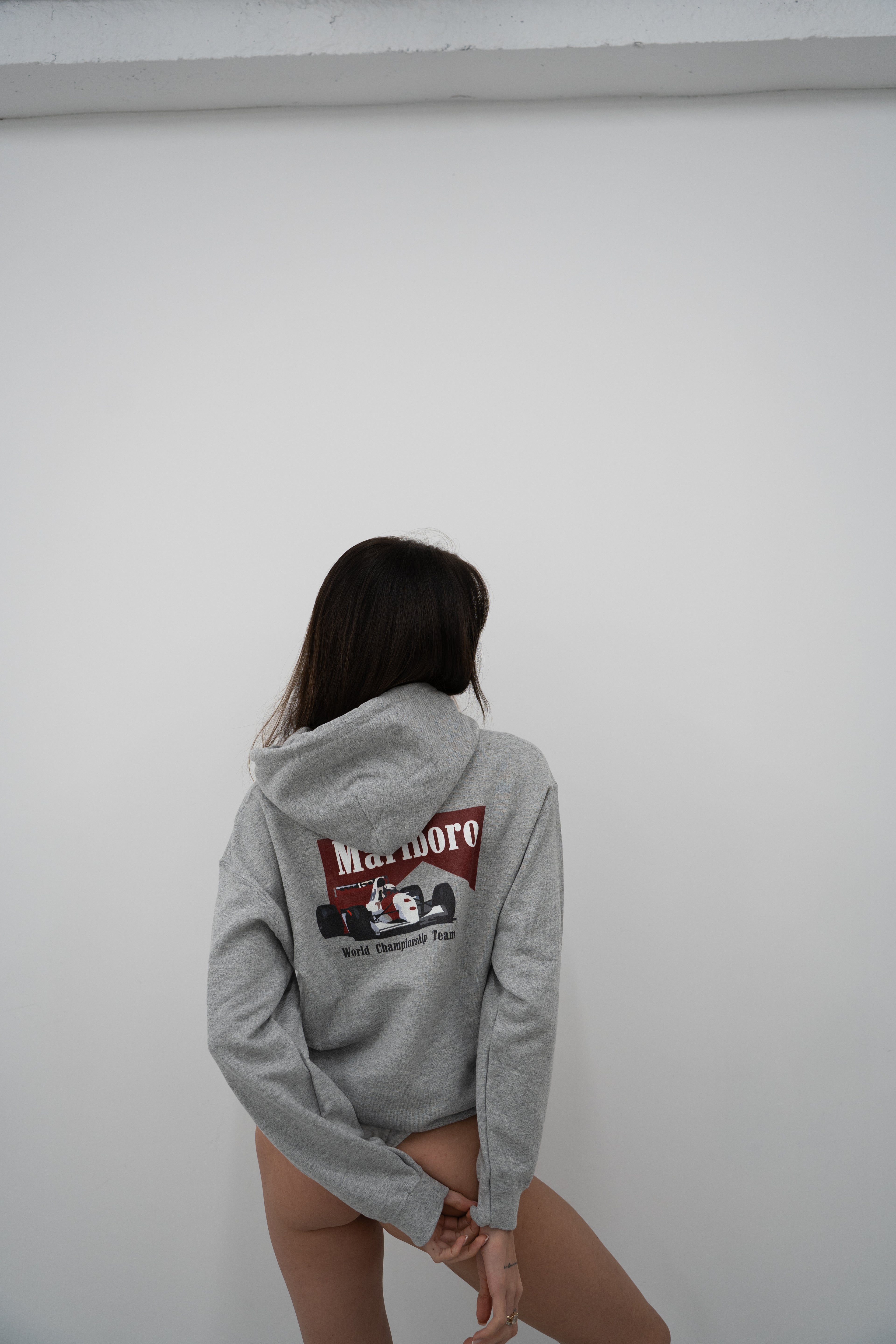 Back view of model wearing Sport Grey Vandox Marlboro World Championship Team Hoodie with Marlboro logo and Formula 1 car graphic, racing inspired Vandox hoodie from luxury starboy old money streetwear collection