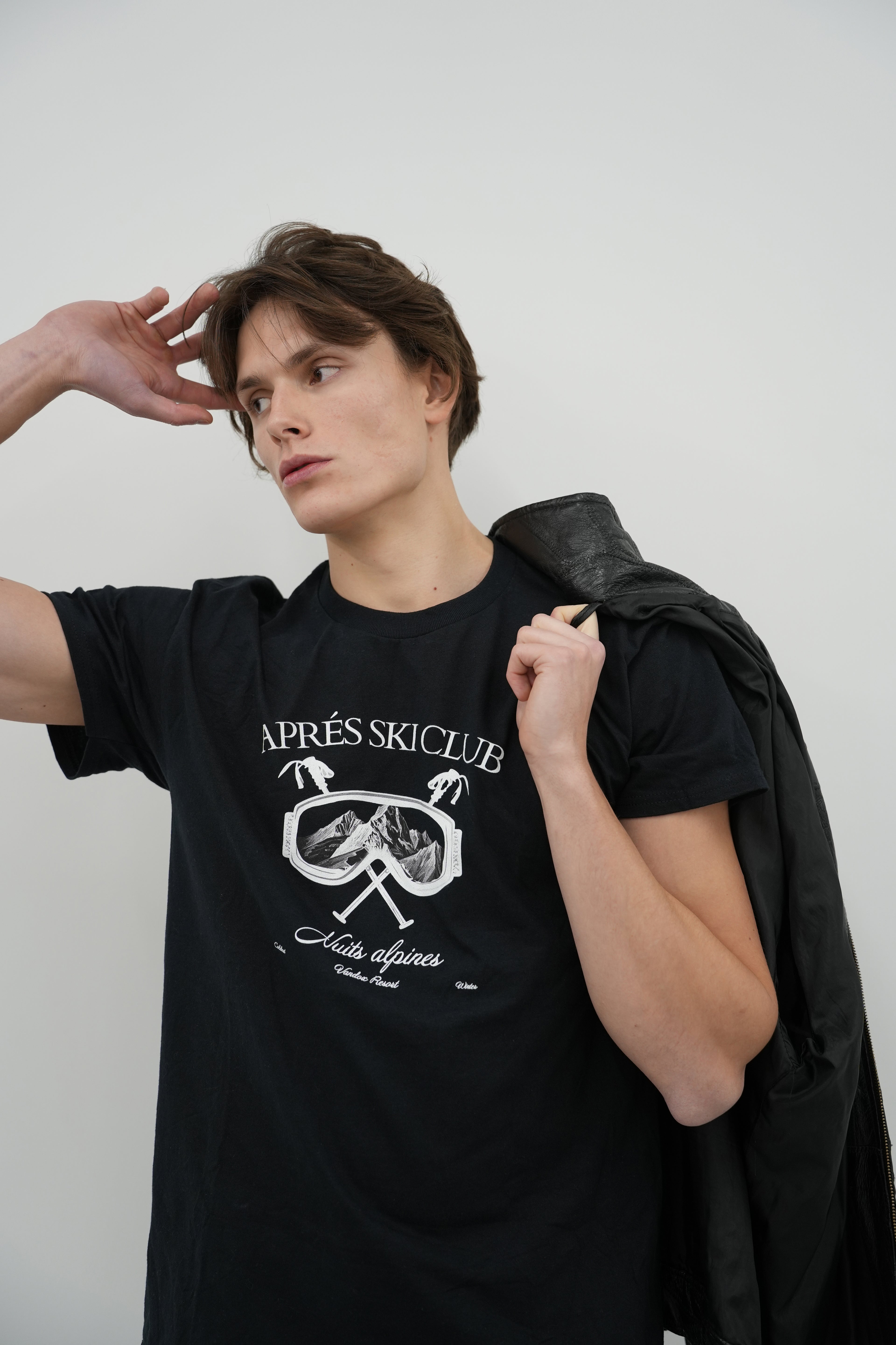 Model wearing deep black Vandox Ski Society T-Shirt with alpine ski goggle graphic and “Après Ski Club” text, luxury starboy old money aesthetic streetwear from Vandox clothing collection