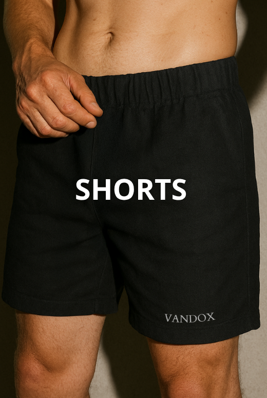 Close-up of a male model wearing black Vandox shorts with an elastic waistband, showcasing the embroidered brand name and the word 