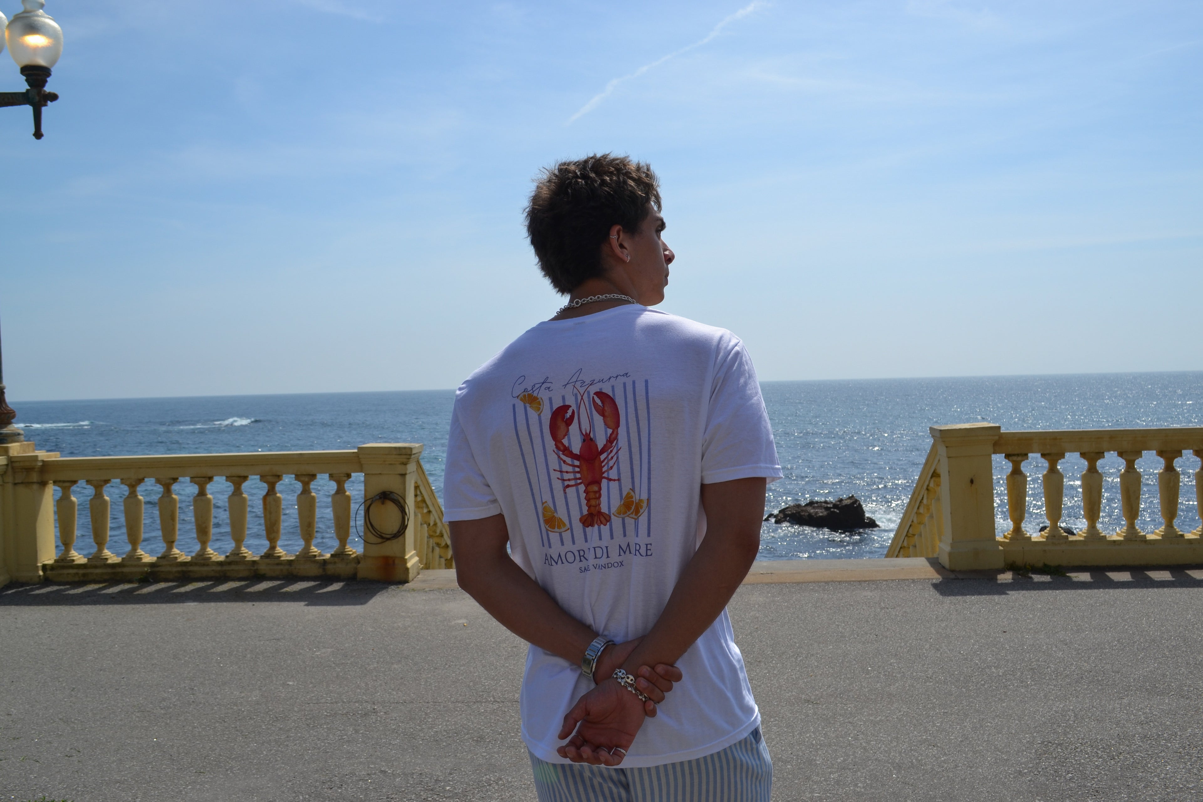 White catch of the day t-shirt, back view, on model. Also wearing vandox linen shorts. 