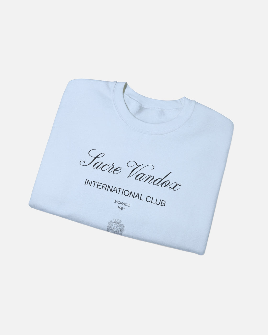 Light blue baby blue Vandox Le Rocher Crewneck, folded front view with Sacre Vandox script, International Club Monaco 1991 text and small crest, luxury streetwear crewneck. Starboy old money crewneck sweatshirt clothes vandox sacrevandox vandox clothes vandox clothing