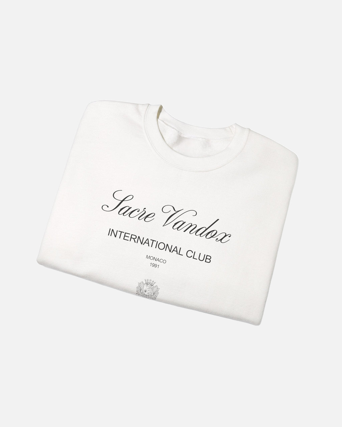 Whtie offwhite eggshell white Vandox Le Rocher Crewneck, folded front view with Sacre Vandox script, International Club Monaco 1991 text and small crest, luxury streetwear crewneck. Starboy old money crewneck sweatshirt clothes vandox sacrevandox vandox clothes vandox clothing