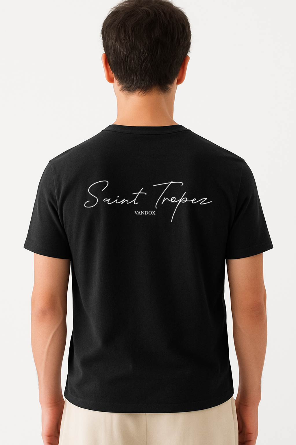 Model wearing the Deep Black Saint Tropez T-Shirt by Vandox, featuring elegant script typography across the back for a refined, coastal-inspired statement look.