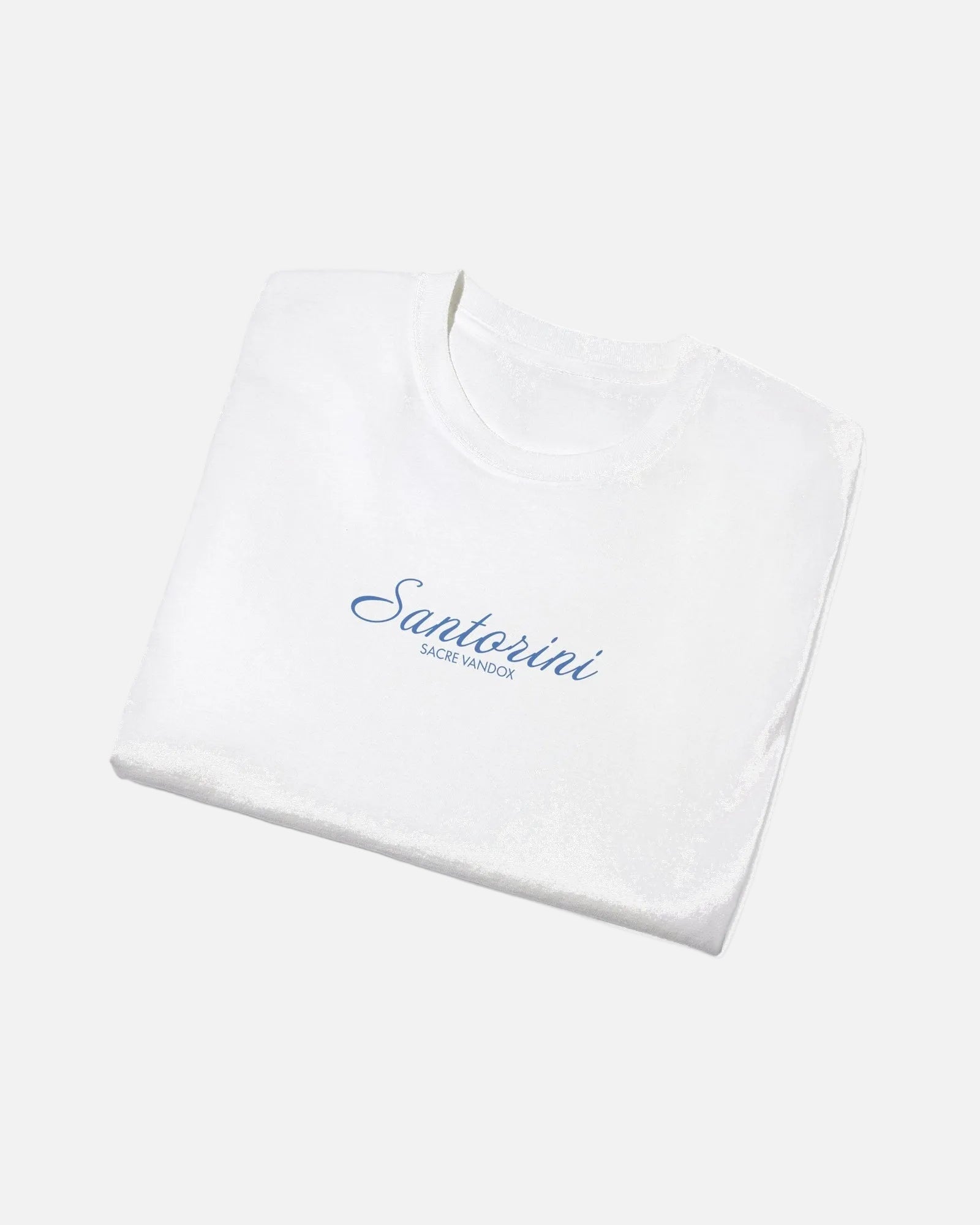 White Vandox Santorini Tee folded view – white premium cotton t-shirt with Santorini script and Sacre Vandox lettering, Postcards collection. Starboy old money shirt tshirt clothes vandox sacrevandox vandox clothes vandox clothing